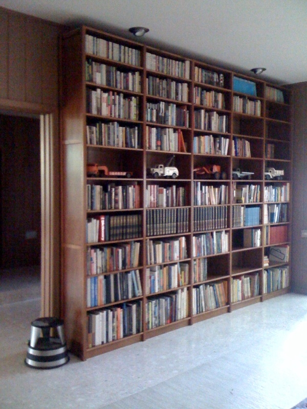 Floor-to-ceiling solid wood bookcase wall holding hundreds of books by Lundia USA