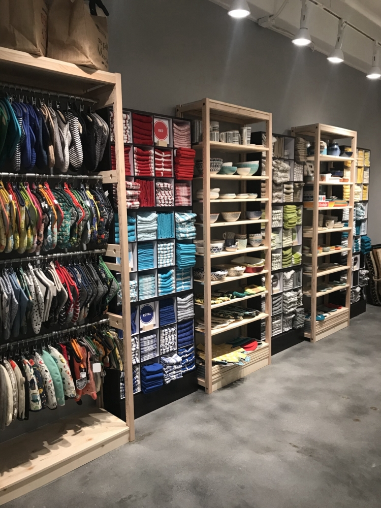 Solid wood shelving in boutique store with knit caps, towels, and dishes