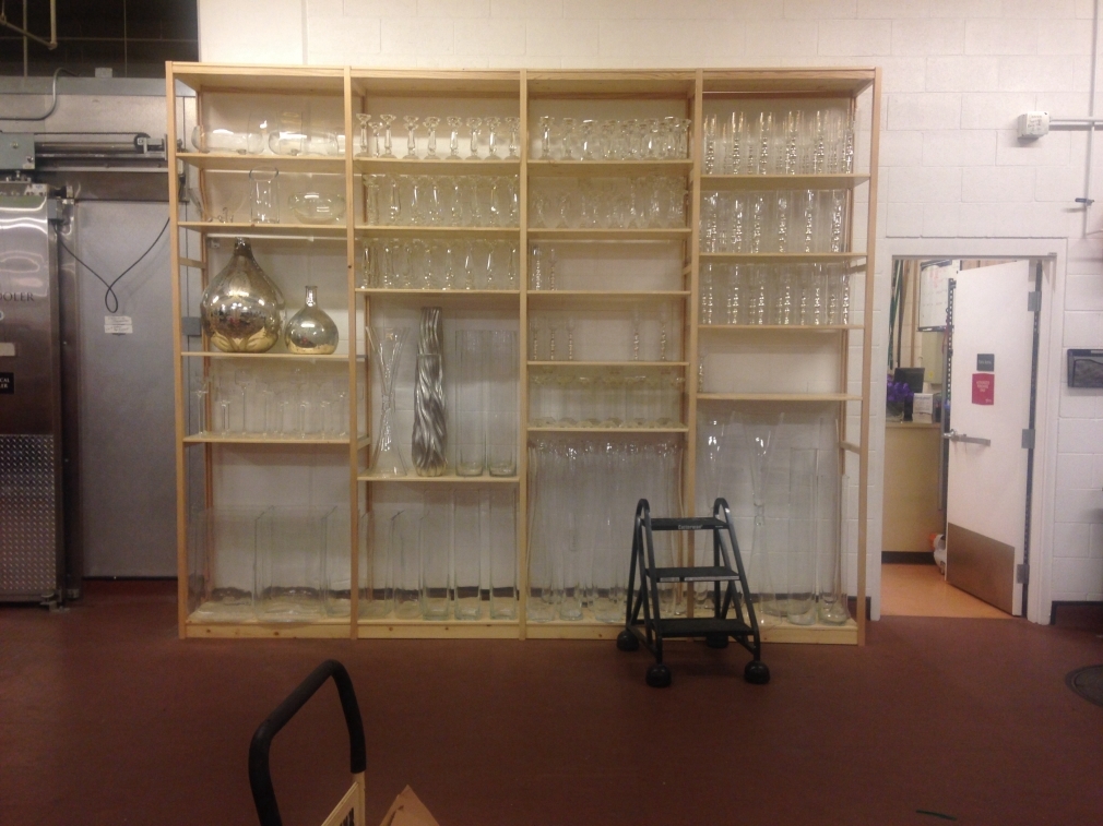 Pine shelving full of clear glass vases in florist warehouse